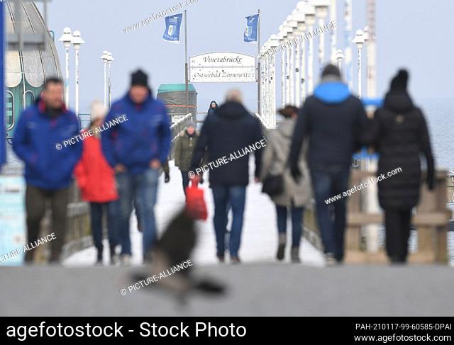 17 January 2021, Mecklenburg-Western Pomerania, Zinnowitz: Walkers walk on the pier in the Baltic Sea resort in the district of Vorpommern-Greifswald