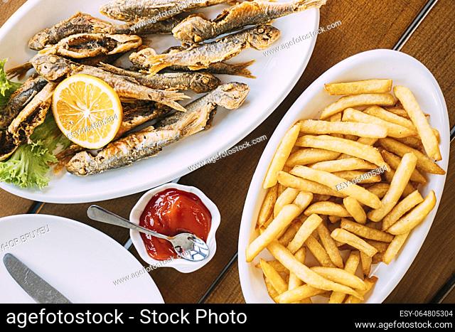 french fries and grilled fishes. fish and chips. Dish with Mullet Fish With orange. Fried fry small fishes