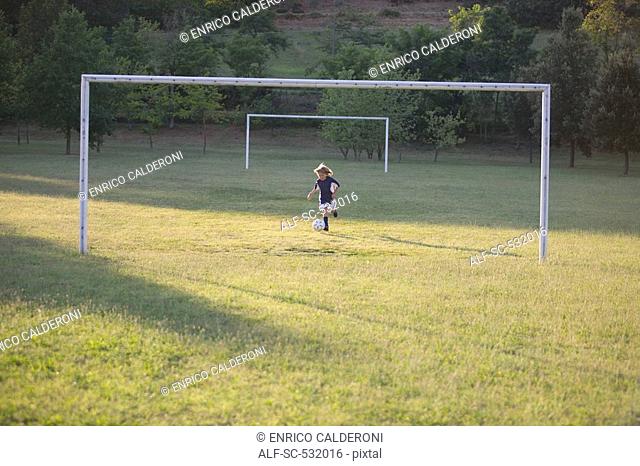 Soccer boy kicking soccer ball at goal post