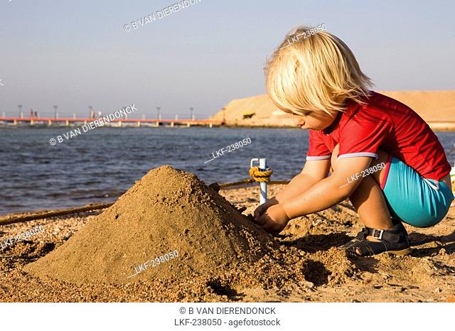 Little child, girl, 3, playing with sand on the beach of the Lamaya Resort, Coraya, Marsa Alam, Red Sea, Egypt