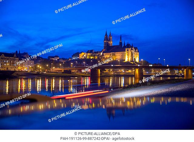 15 October 2019, Saxony, Meißen: The illuminated Albrechtsburg Castle and the cathedral of Meissen are reflected in the evening in the Elbe