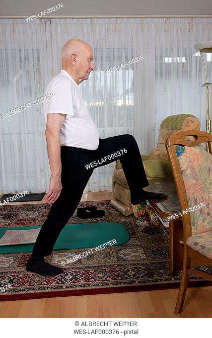 Old man making exercises in his living room