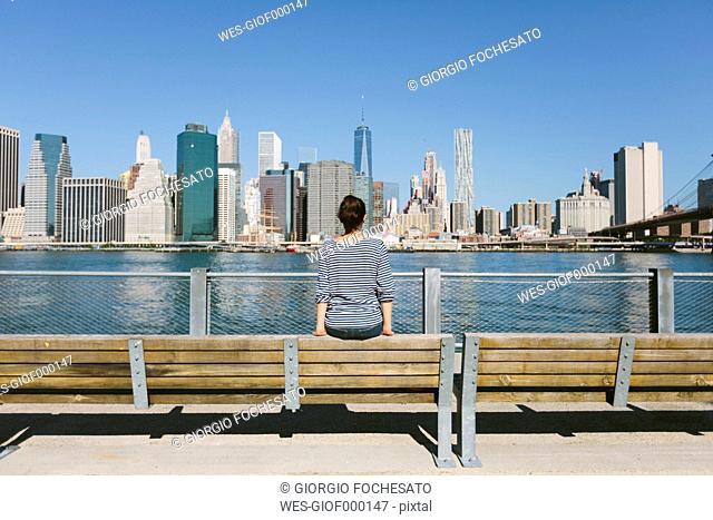USA, New York City, back view of young woman looking at skyline