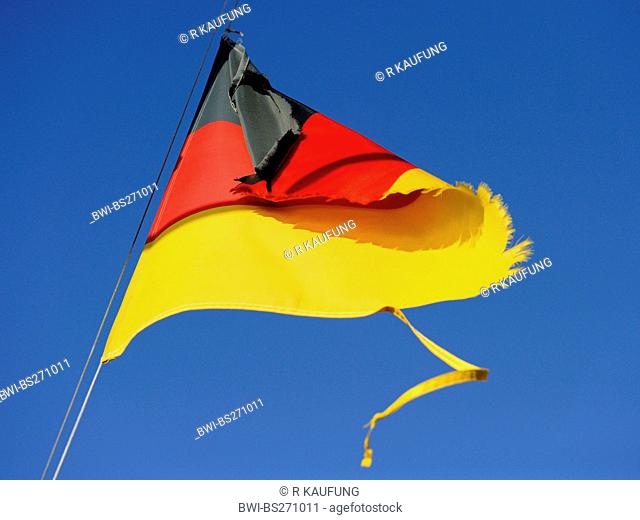 German national flag torn in the wind ists waving in front of blue sky