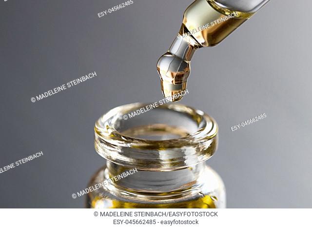 A drop of essential oil is being dropped into a bottle