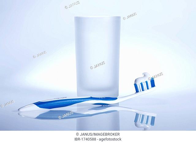 Blue and white toothbrush with a glass of water