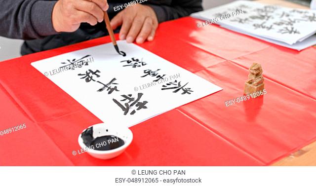 Man pratice chinese calligraphy for lunar new year, words mean wish you a prosperous Year