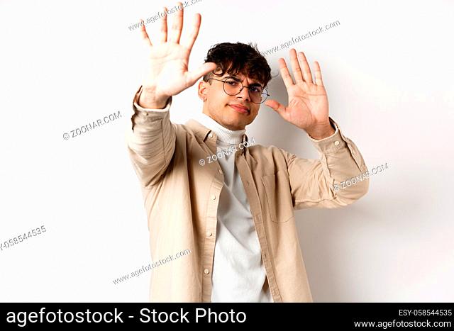 Image of reluctant and annoyed man raising hands up to block offer, refusing and asking to stop, telling no, declining something, standing on white background
