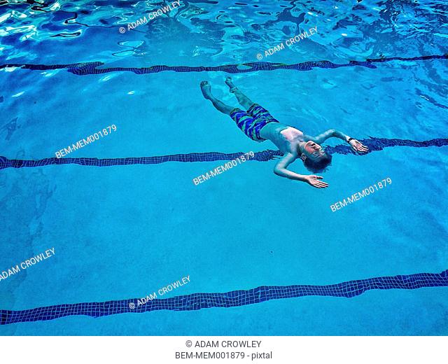 Caucasian boy floating in swimming pool