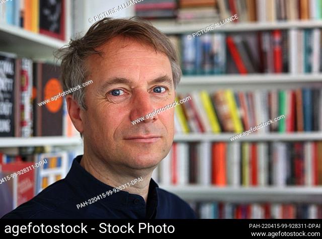 14 April 2022, Bavaria, Munich: Jo Lendle, writer and publisher of Carl Hanser Verlag, stands in front of books in his office