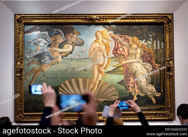 FLORENCE, ITALY - FEBRUARY 18, 2019: Tourist hands lifting cell phones to take picture of famous Birth of Venus painting in museum