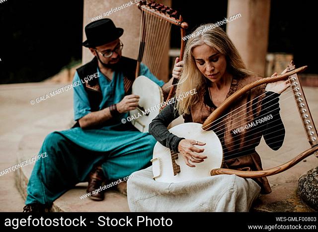 Female with male playing lyra musical instrument on staircase