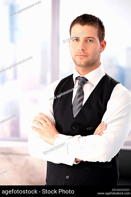 Portrait of young businessman standing arms crossed, wearing waistcoat