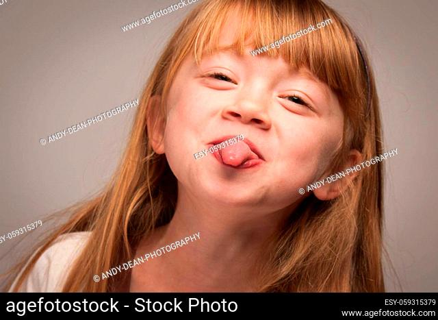 Fun Portrait of an Adorable Red Haired Girl on a Grey Background