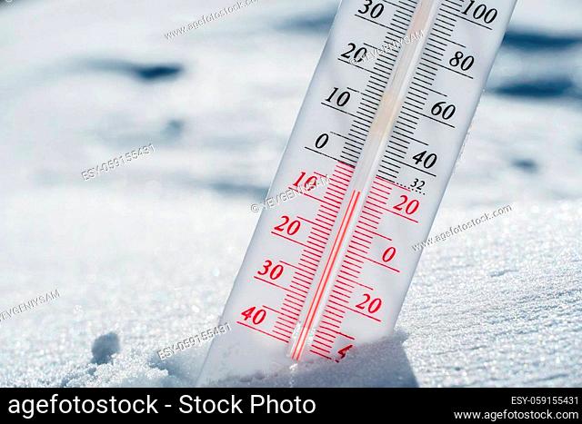 The thermometer lies on the snow in winter showing a negative temperature.Meteorological conditions in a harsh climate in winter with low air and ambient...