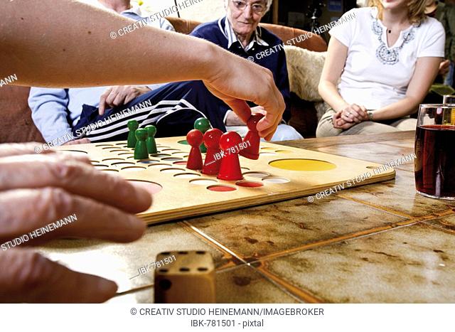 Senior citizens playing Ludo with over-sized game pieces at an old-age home