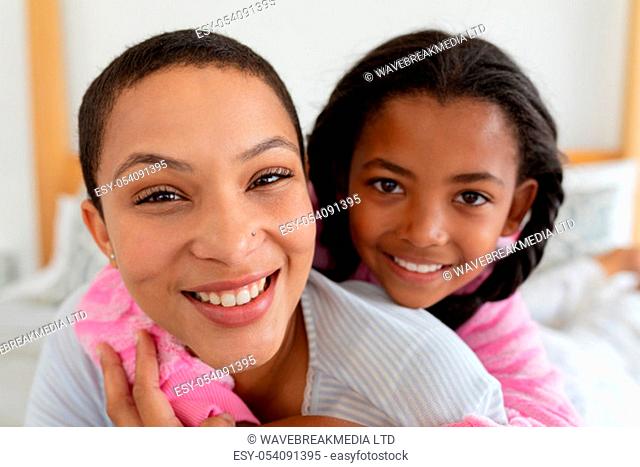 Front view of African american mother and daughter embracing each other in bedroom at home