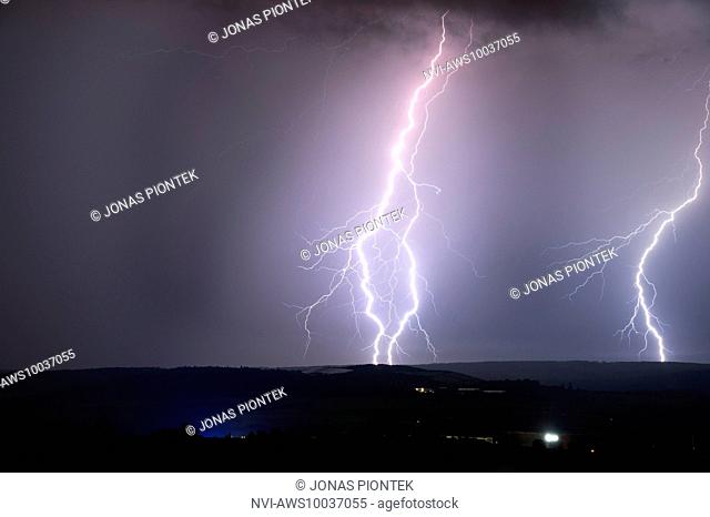 Branched cloud-to-ground lightnings behind a town in Taunus, near Usingen, Hessia, Germany