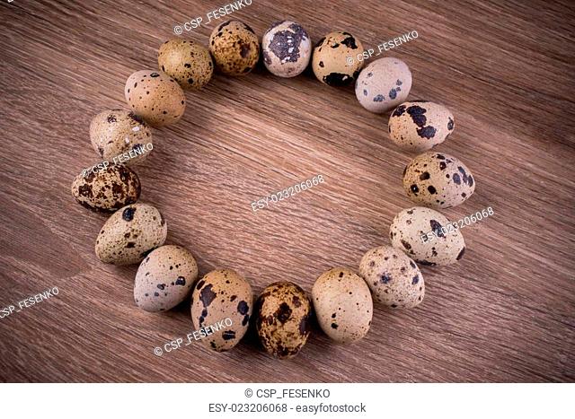 Quail eggs in circle on wooden background
