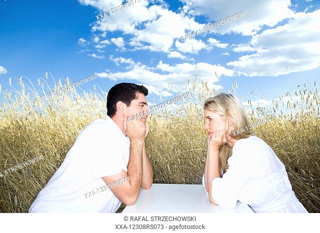 couple siting on field and looking into eyes