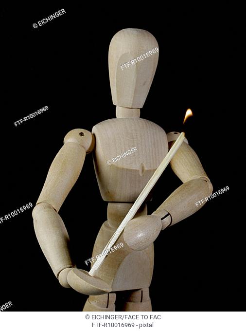 A wooden figure holding a lighted matchstick
