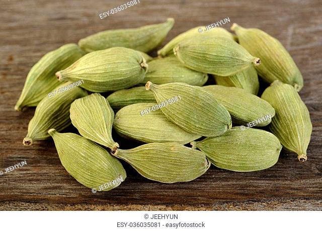 green cardamom pods on wooden background