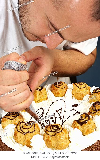 A pastry chef decorating a cake with whipped cream