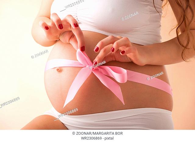Pregnant belly with pink ribbon