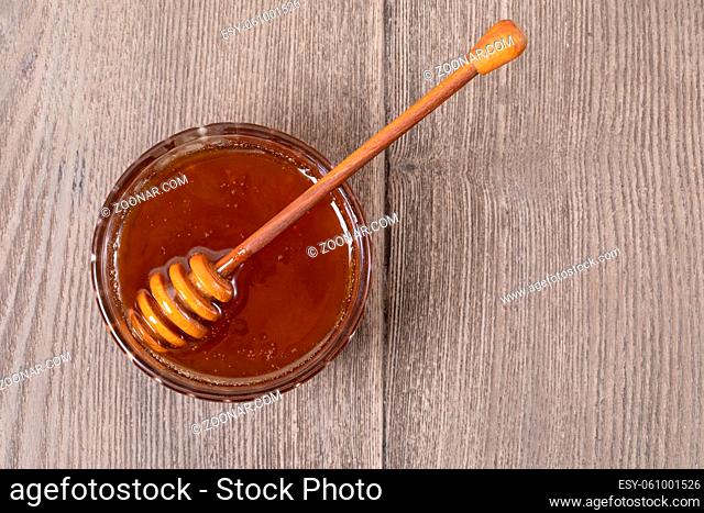 Honey in a transparent jar with a honey spoon