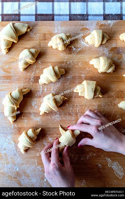 Woman rolling croissant dough on cutting board