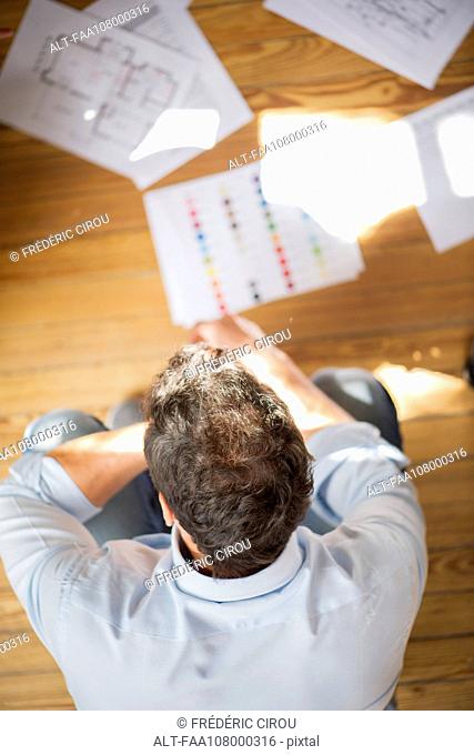 Man contemplating blueprints and color swatches