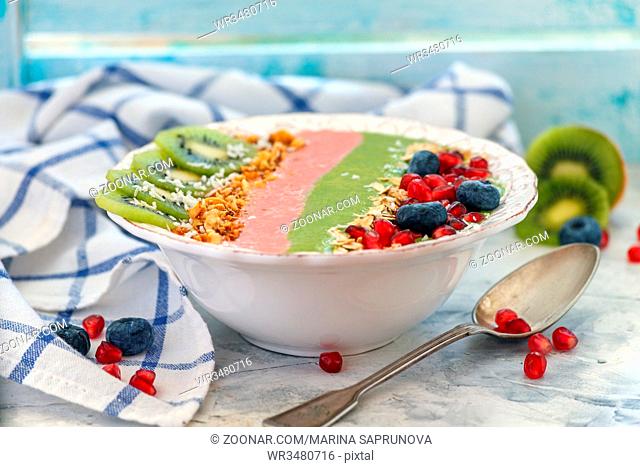 Smoothie bowl of spinach and strawberry with banana and berry and fruit topping on old kitchen table, selective focus