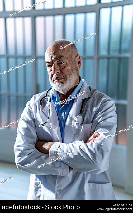 Serious senior doctor standing with arms crossed