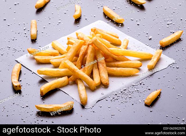 fresh yellow fries on a black table with sea salt