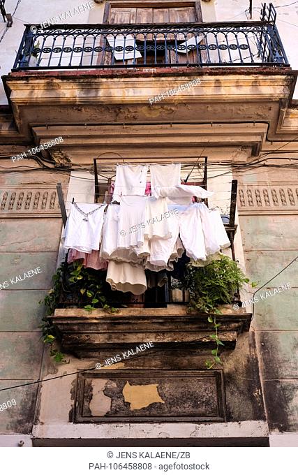 21.06.2018, Cuba, Havana: Washed laundry hangs on a balcony of an old dilapidated residential building in a street of the old town
