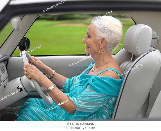 Glamorous senior woman driving in car