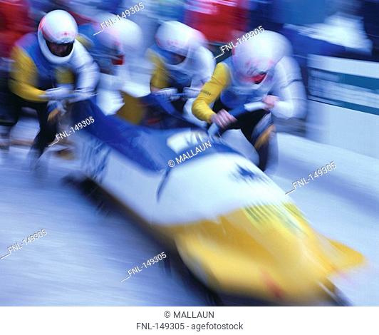 Four people with bobsleigh, blurred
