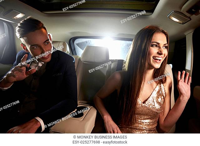 Young couple in the back of a limo looking out of the window