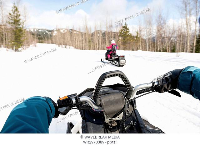 Mid-section of woman riding snowmobile