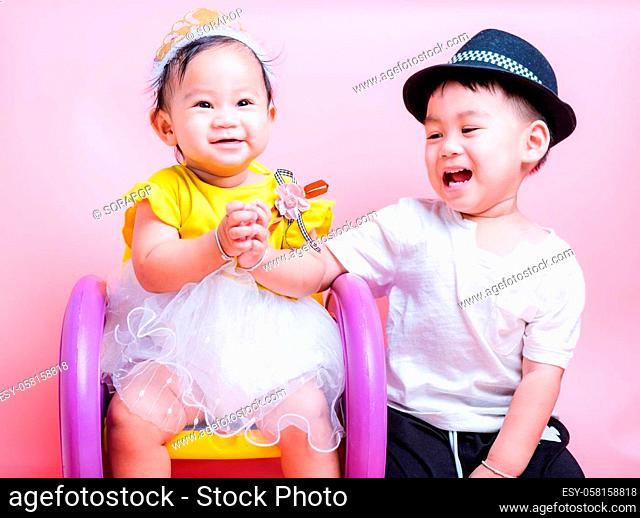 Asian Little brother and her baby girl in beautiful dress sitting on chair, Family with children in studio on pink background