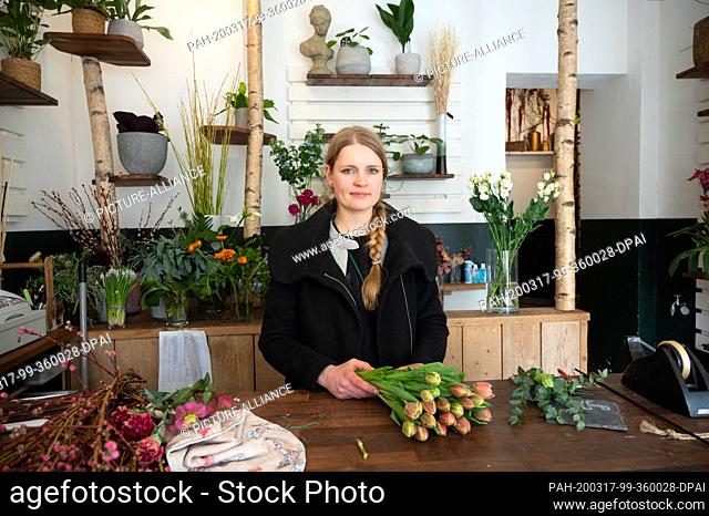 17 March 2020, Hamburg: Laura Blöchl, owner of a flower shop, stands behind the counter. Due to the corona virus, Blöchl has to close her flower shop