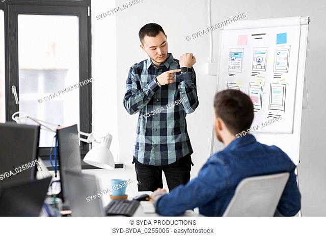 man showing smart watch to creative team at office