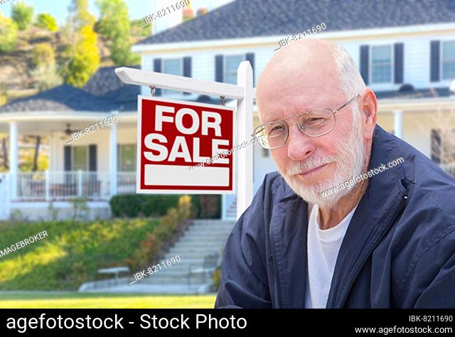 Senior adult man in front of home for sale real estate sign and beautiful house