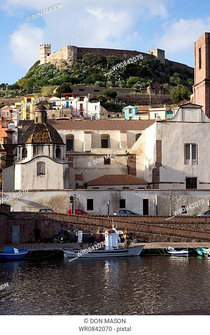 Bosa harbour and waterfront. Moored fishing boats along the Temo River estuary. Castello de Serravalle on the hilltop