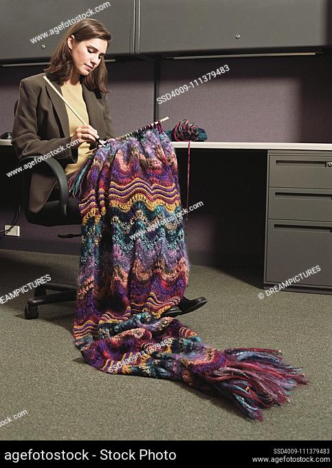 Businesswoman sitting at a desk knitting