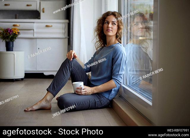 Woman looking away while sitting on floor at home