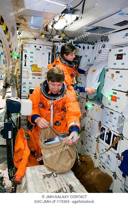 NASA astronauts Nicole Stott and Michael Barratt, both STS-133 mission specialists, participate in a post insertionde-orbit training session on the middeck of...