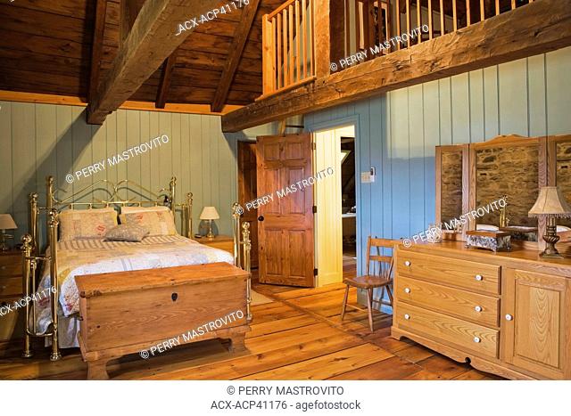 Brass bed and furnishings in the master bedroom on the upstairs floor of an Old Canadiana 1722 cottage style fieldstone and wooden siding Residential Home