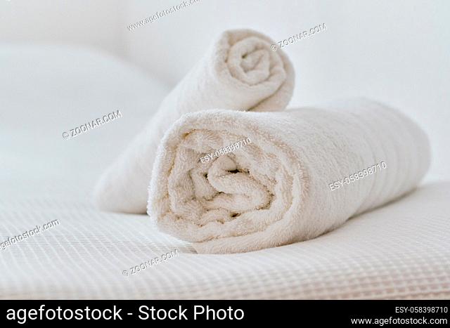 Folded white color towels lying on bed in bedroom, close up view