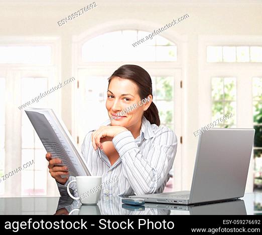 Young woman reads a paper document. It is early morning in a light and clean home interior dominated by white and soft tones